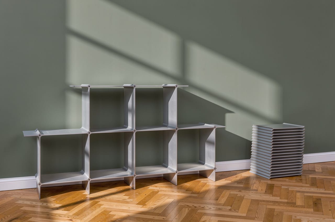 Modular aluminium shelving system — a shelf in silver with six compartments, beside it the profiles stacked flat