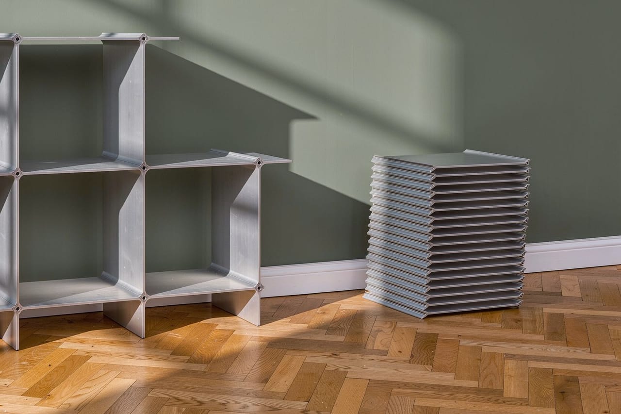 Montique shelf in silver, beside it the same profiles laid flat in a stack